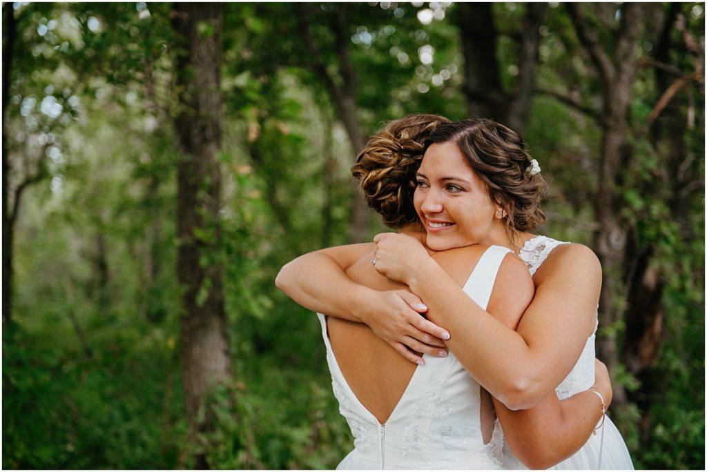 two brides hugging during their first look at the Four Rivers Environmental Center