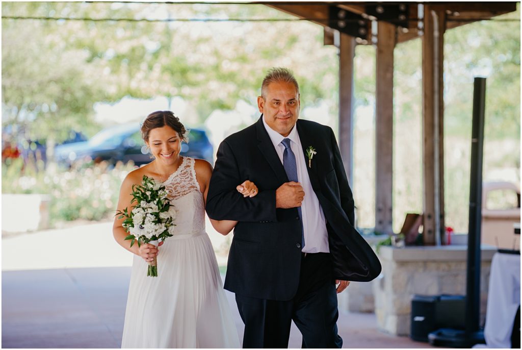 a father leading his daughter down the isle at an outdoor wedding