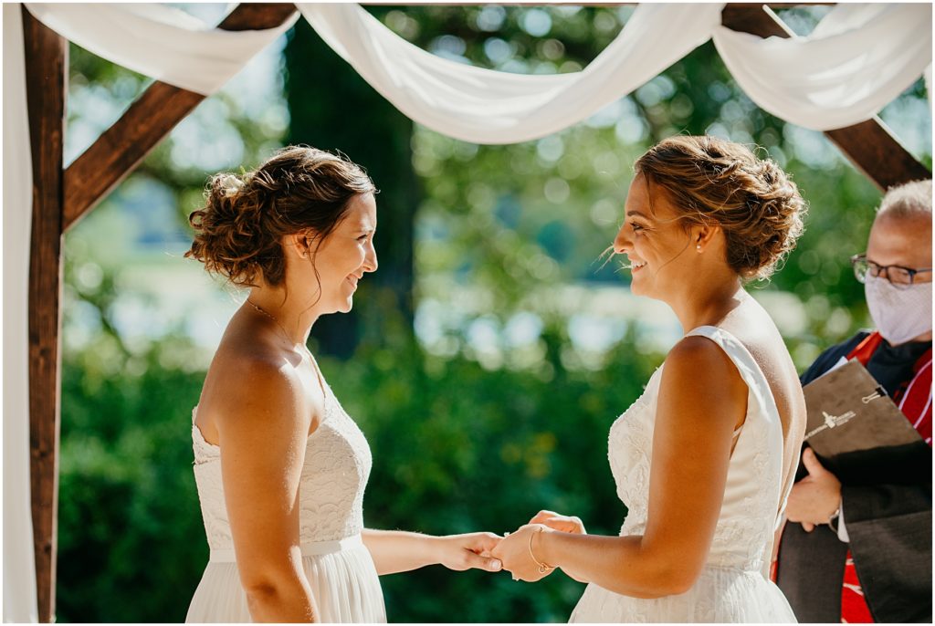 a bride putting a ring on her brides hand during their intimate wedding