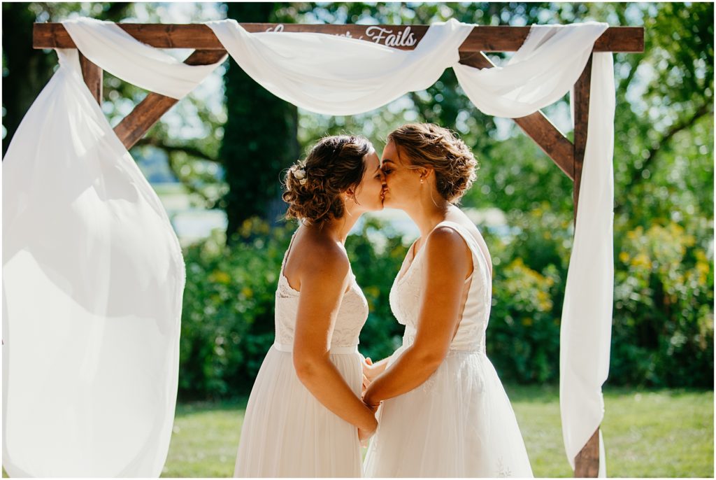 two brides kissing for the first time during their wedding at the Four River Environmental Center