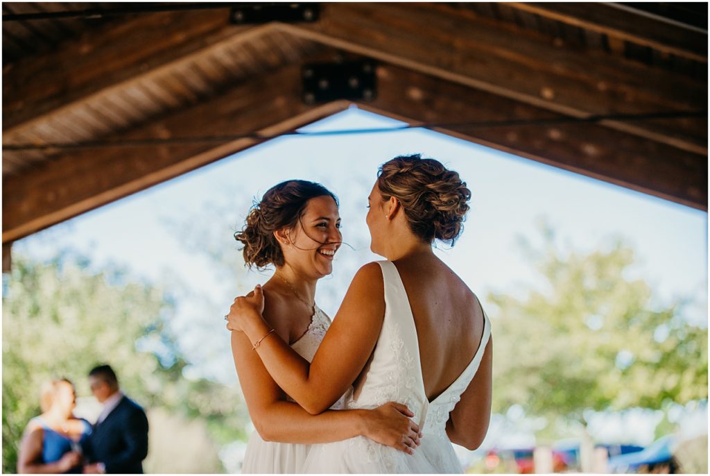 a bride laughing as her bride swings her during their first dance at their intimate wedding