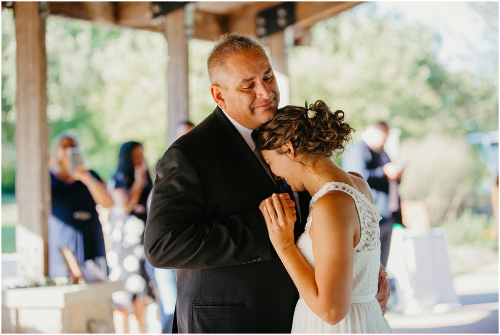 a bride resting her head against her fathers chest during the father daughter dance at an intimate wedding