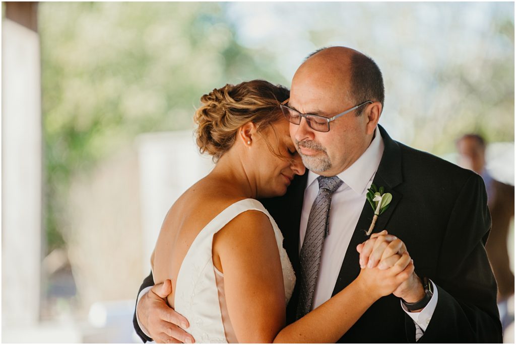 the bride resting her head on the fathers shoulder during the father daughter dance