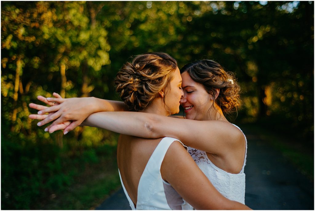 two brides standing close together during suns set during their intimate wedding