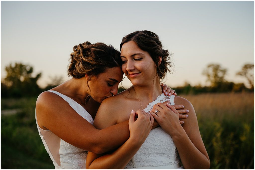 two brings standing close together during sunset at their intimate wedding